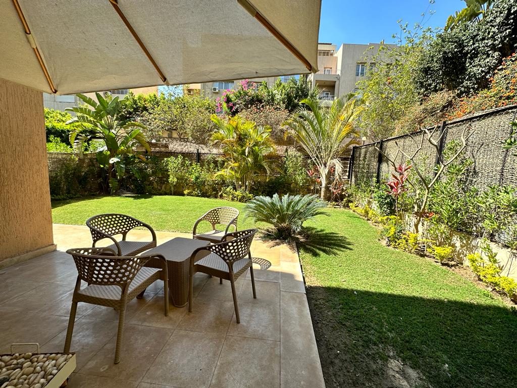 Private garden with a table, chairs and a large sun umbrella