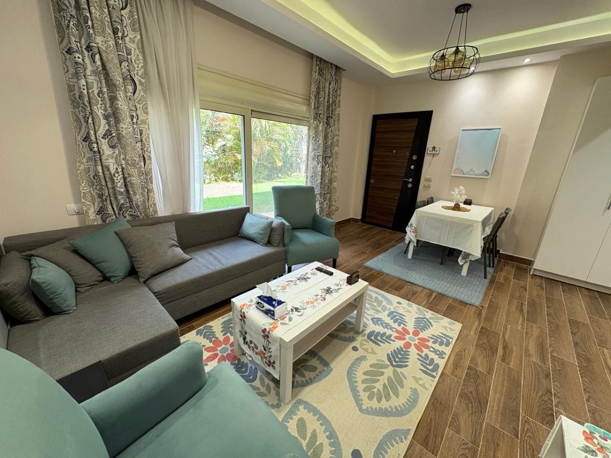 Living room with a sofa, two armchairs and garden views through the glass doors