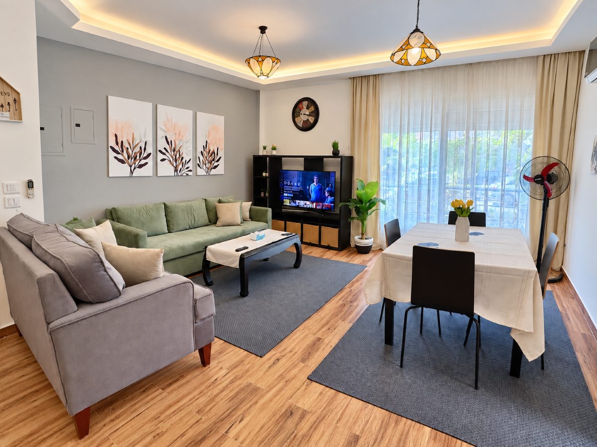 Living and dining area with a sofa, dining table, Smart TV and tall windows