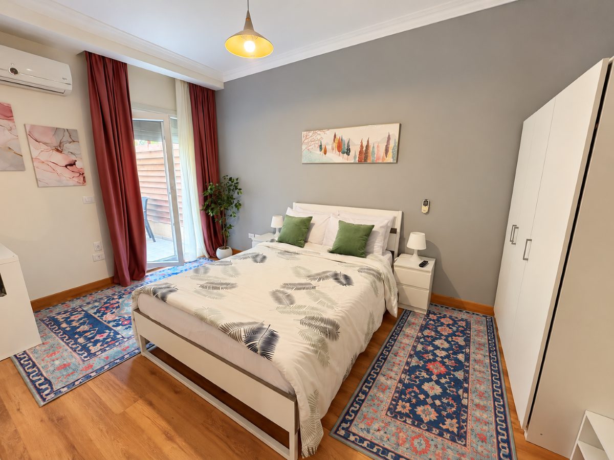 Bedroom with a queen bed, bedside tables, full-length curtains and patterned rugs
