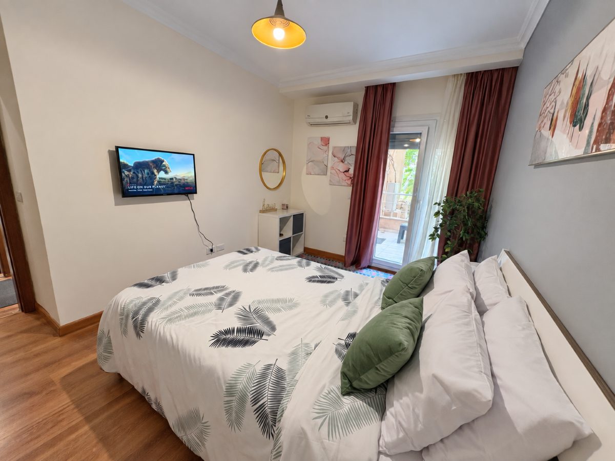 Bedroom seen from the other side, showing the television and the balcony door